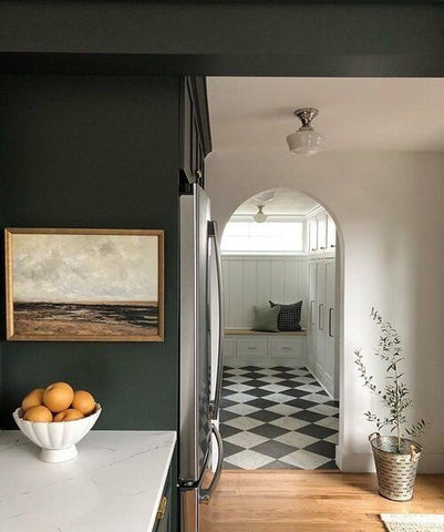 A dark green wall next to an arched doorway leading into a mudroom with checkered flooring