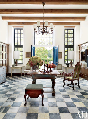 Black and white checkered floor in a bright glass window entryway with wood beams and painted wood doors