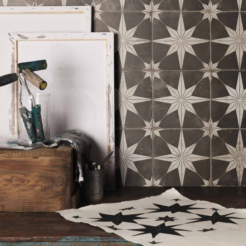 Star Dark Night Patterned Floor Tiles 45x45cm. Victorian wall tiles in a studio setting, with canvas, paint brushes and wooden paint storage box in front, on a wooden table.