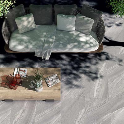 Outdoor Porcelain tile 60x120cm Nexus silver in a garden setting with garden sofa and coffee table in a shady nook.