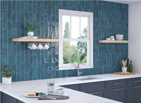 nissel blue kitchen wall tiles in kitchen setting with dark blue kitchen cabinets, white worktop with inset sink and wood shelves either side of a window