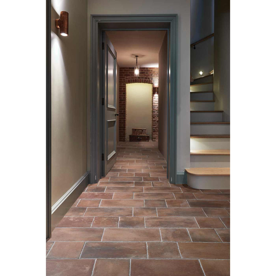 Brewhouse Rectangle tiles 22.5x45cm. Terracotta effect tiles as hallway tiles. Grey painted walls leading to a doorway. Wooden stairs to the right.