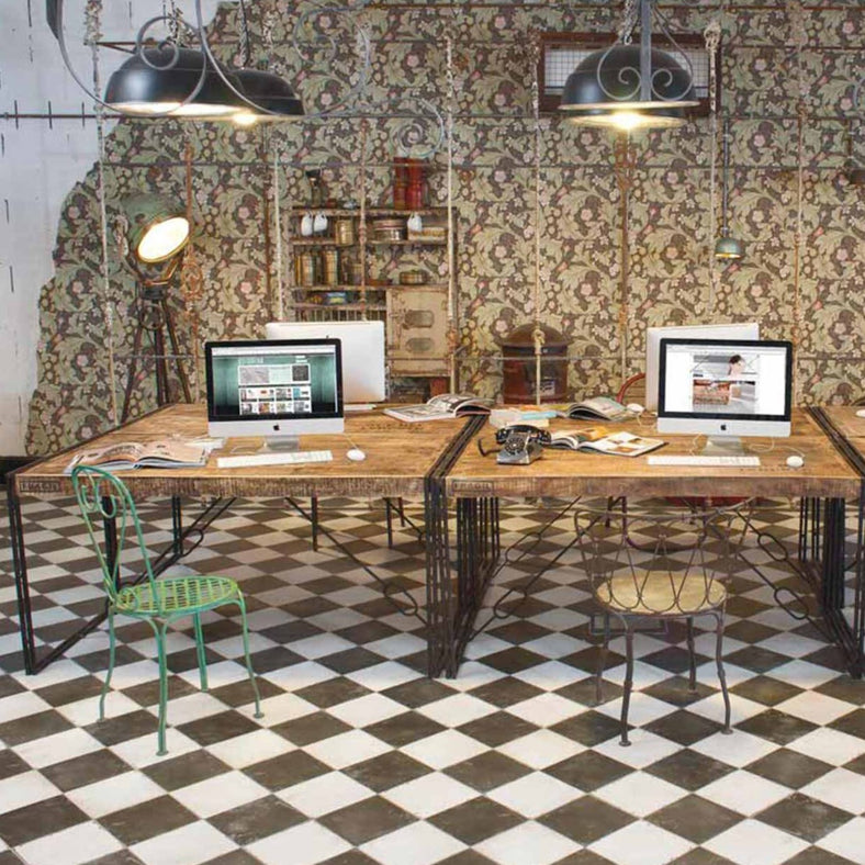 Chequer black & white floor tile 45x45cm in an office setting surrounded by Victorian era decor. Desktop computers are on top of wood tables with metal chairs. Old and peeling Victorian decor wallpaper is on in the background with industrial black metal pendant lights hanging low from the ceiling.