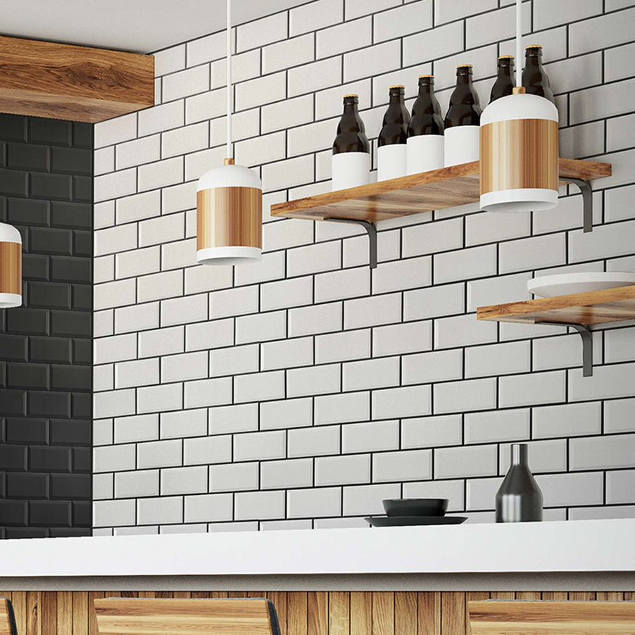 Metro Matt White Bevelled Brick tile 10x20cm. Subway tiles as kitchen wall tiles in a kitchen setting with wooden units, white worktop and wooden shelving with bottles on.