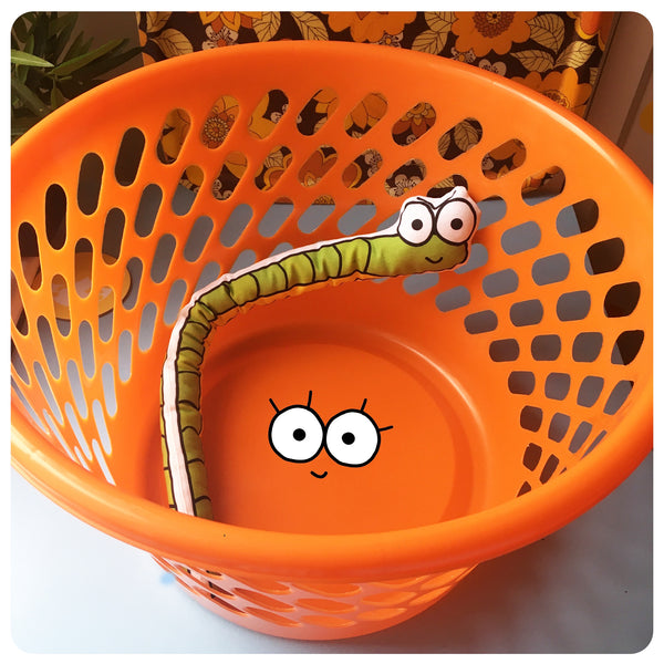 A bright orange washing basket with a cheerful snake toy inside