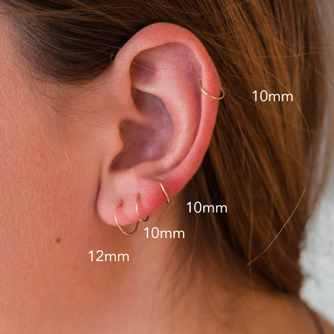 small Hoop earring sizes on ear of a girl model. there are 3 hoop earrings  in the earlobe and one cartilage hoop earring