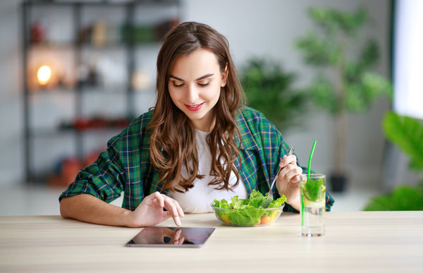 Women eating salad while watching tablet