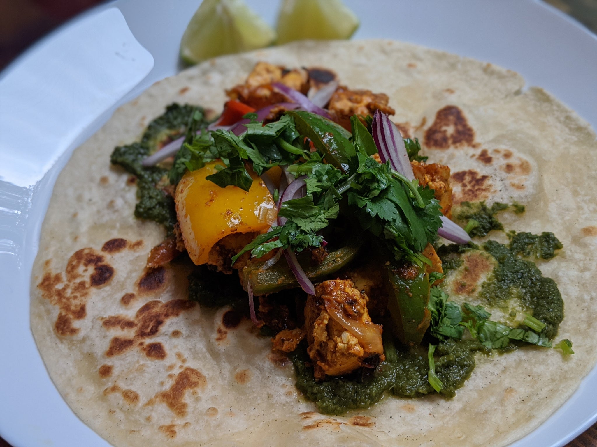 Kathi roll being prepped with cilantro chutney and paneer/veggie mix 