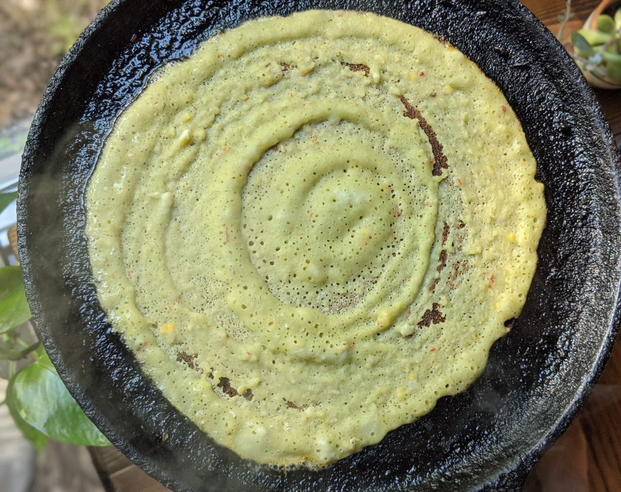 Delicious savory pancake made with rice, lentils and SpiceFix Moringa powder being cooked on a cast iron pan 