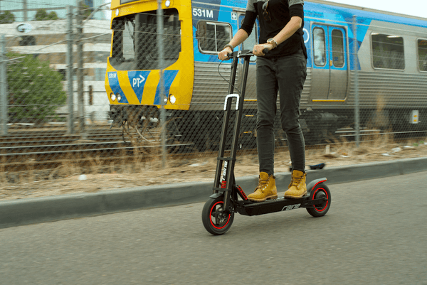 Electric scooter being ridden next to a train