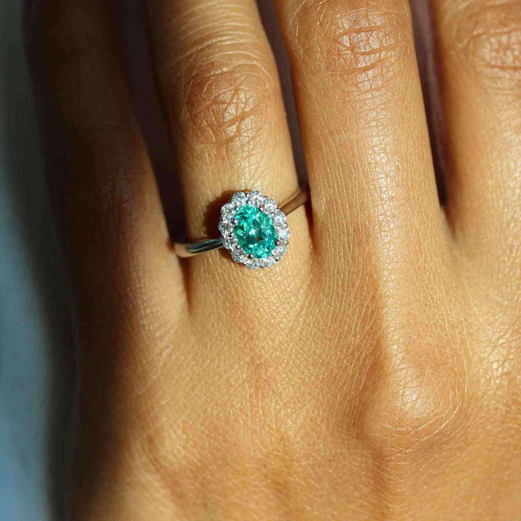 hand wearing ring with green chrysoberyl gemstone and diamond halo