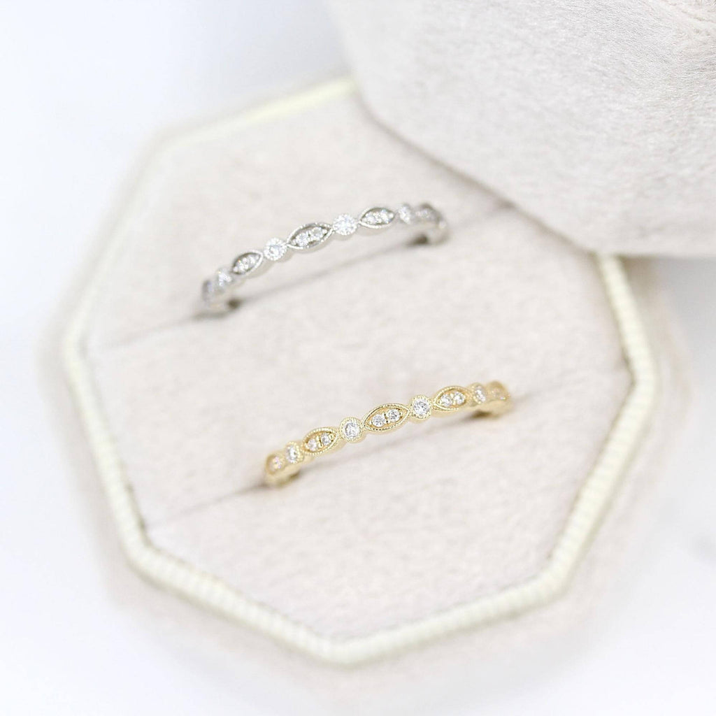 White velvet ring box holding white gold and yellow gold diamond wedding bands
