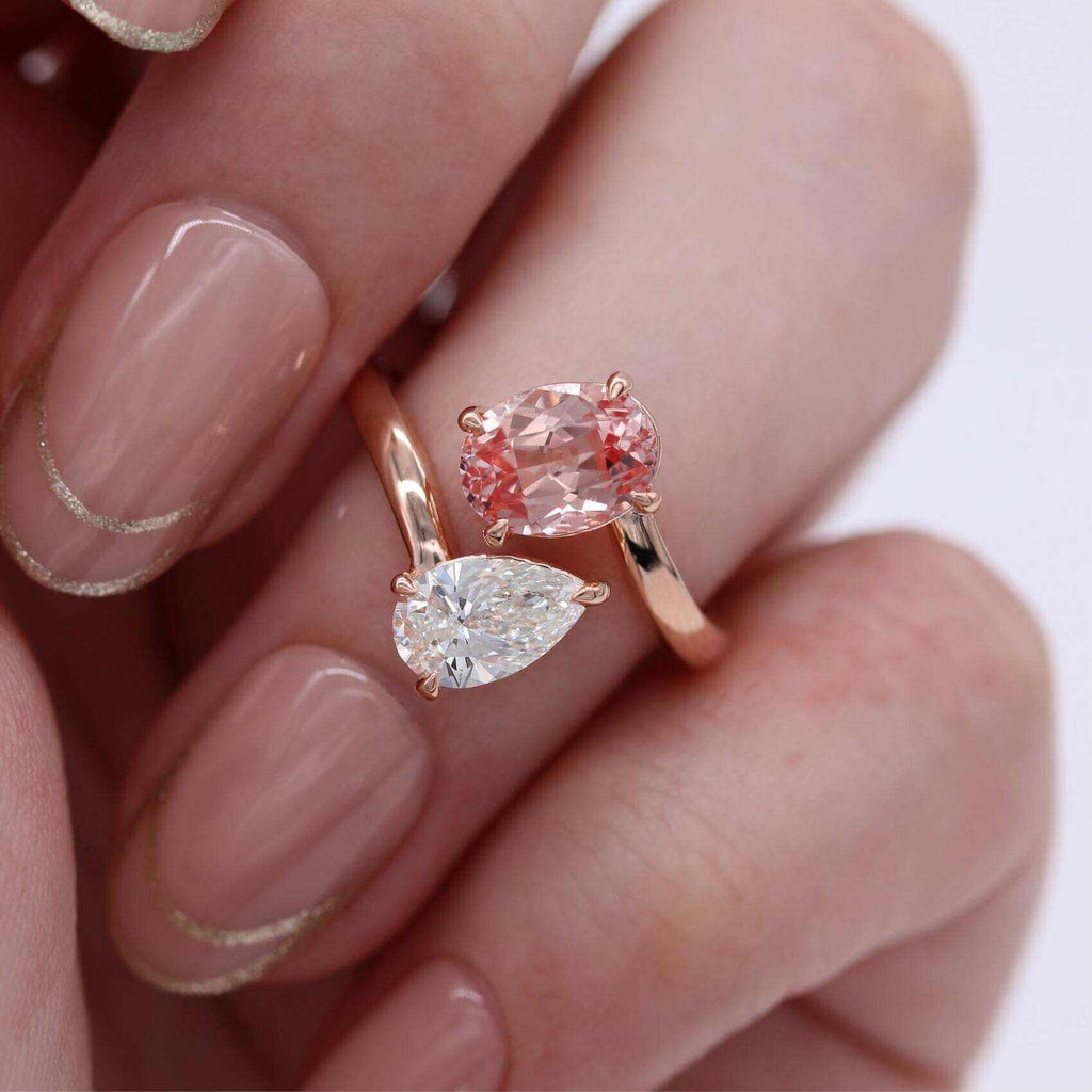 hand showing diamond and peachy-pink sapphire toi et moi ring in rose gold