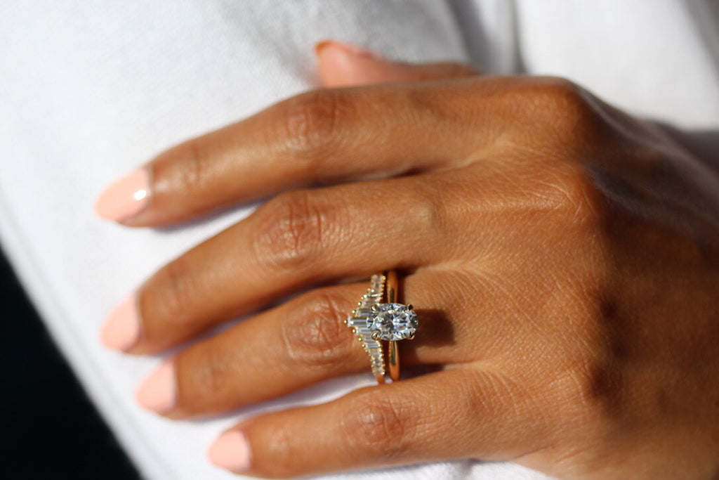 oval solitaire engagement ring stacked with graduated baguette diamond band on hand