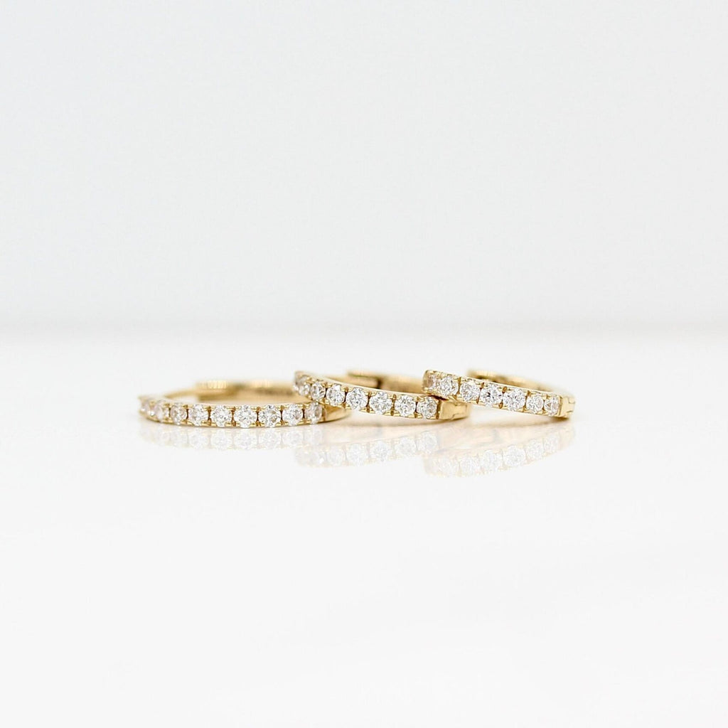 three sizes of gold and diamond earrings stacked on each other