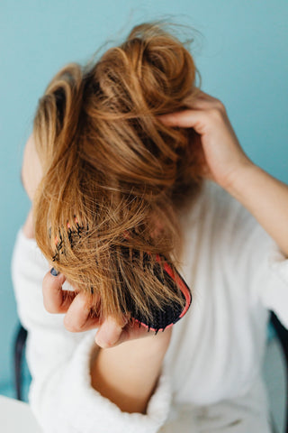 Frau kämmt sich mit Bürste die Haare