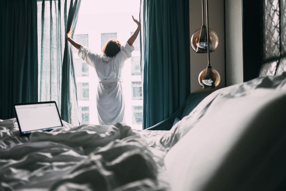 A person opening a window in a hotel room.