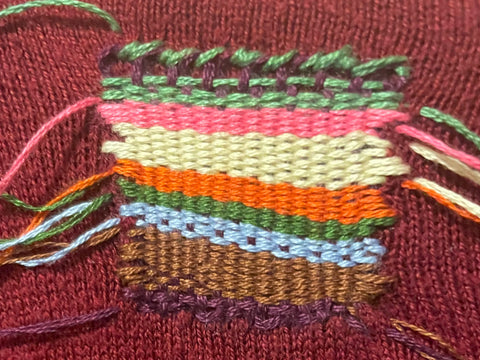 Close up of multicoloured darned patch, horizontal stripes created by changing weft rows every few passes.