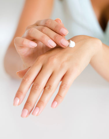 lotion being applied to hand with pink nail polish
