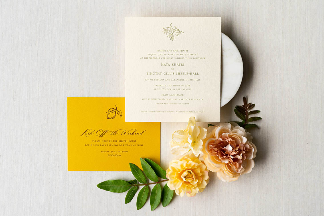 Turmeric yellow letterpress welcome dinner invitation with custom illustrated lemon design, and letterpress ceremony invitation with olive illustration and text on a cream stock