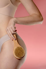 woman's arm holding shower brush on hip