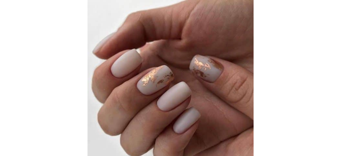 Ongles nudes doux avec détails de feuilles d'or