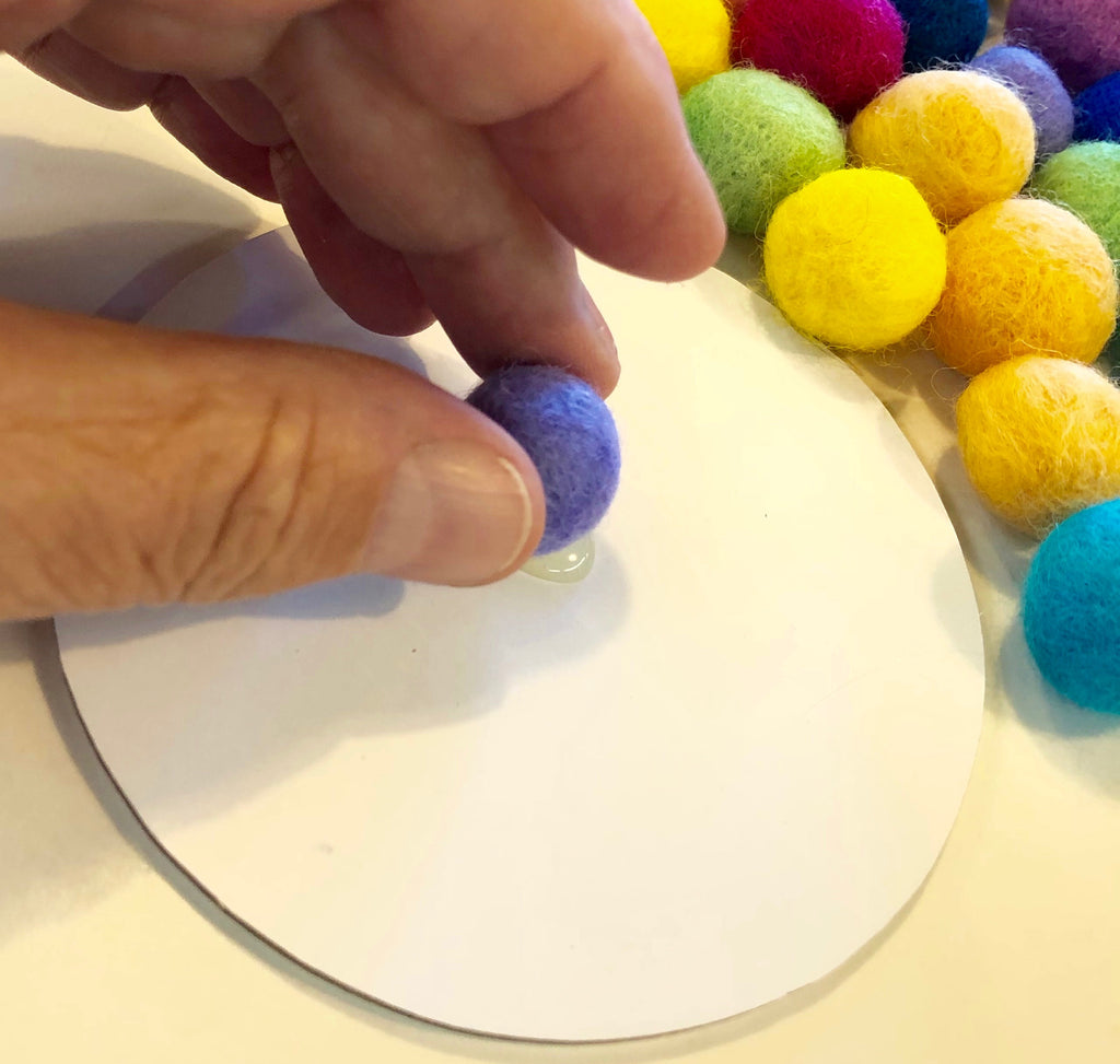 Applying Wool Pom Pom to hot glue dot