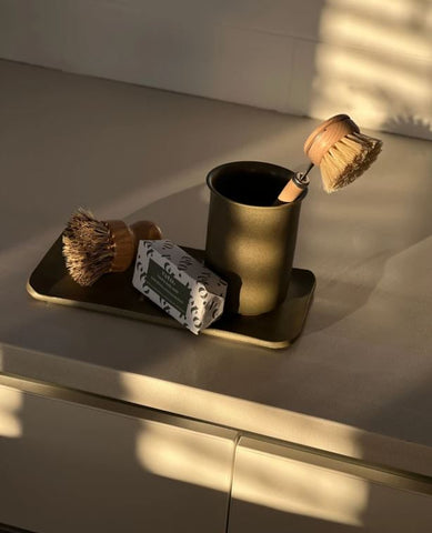 green ceramic storage tray and cup on benchtop with dish brush, soap and wooden scrubber