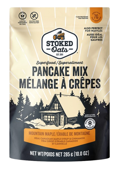 Stoked Oats Pancake Mix packaging with a mountain cabin and trees illustration.