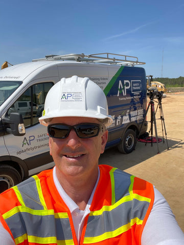 Man in a hard hat and orange safety vest standing in front of an AP Safety Training production van.