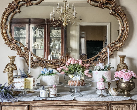 Faux cakes on buffet table with tulips and gold vintage mirror on wall behind