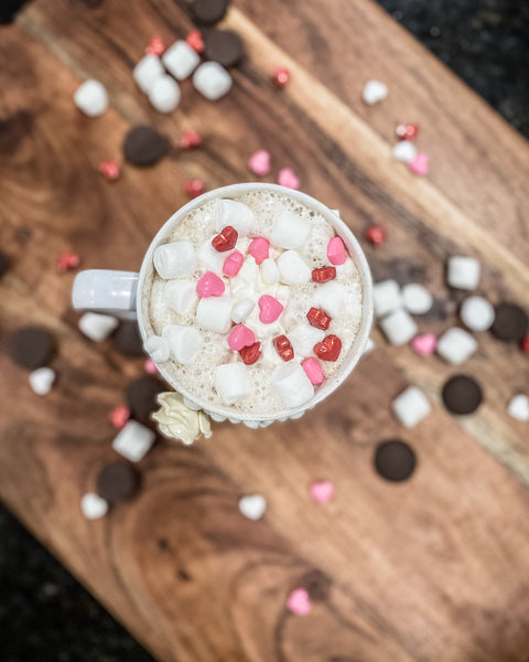 Flatlay cocoa cup with chocolate marshmallows and candy hearts