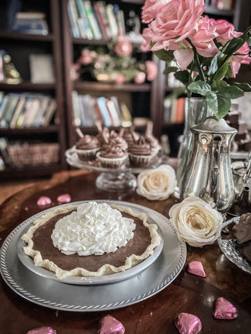chocolate pie with whipped cream on dessert table with pink roses