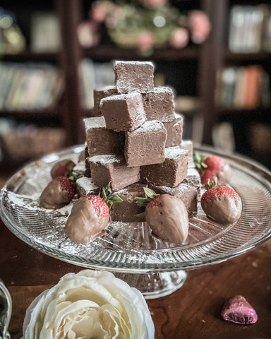 homemade fudge on crystal cake stand with chocolate dipped strawberries