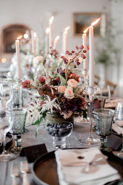 Flower arrangement with taper candles on table