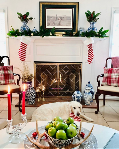 Fireplace decorated in Christmas decor with red candles on table and green apples