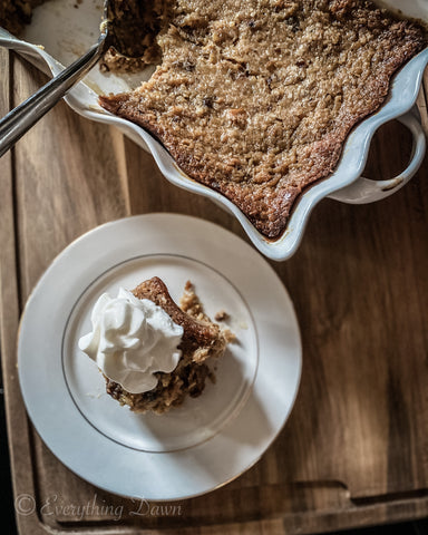 Bread pudding in white baking dish with a slice beside on a dessert plate