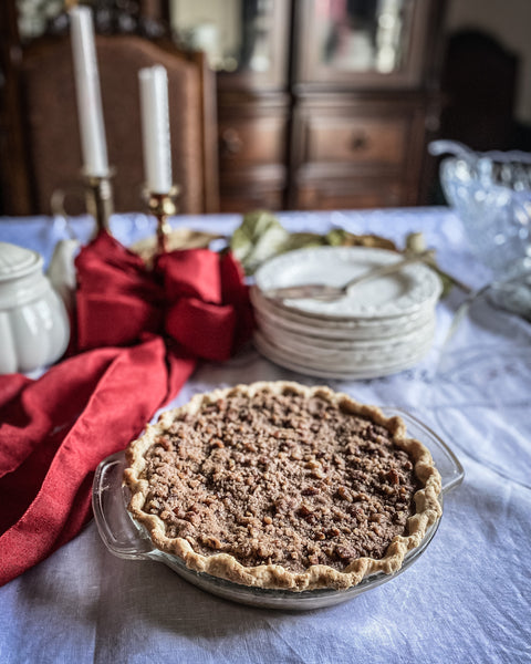 Pumpkin pecan pie on table with red ribbon and plates behind