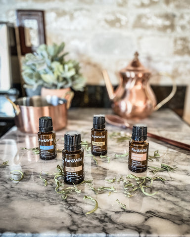 Far & Wild essential oils on white marble counter with copper teapot behind