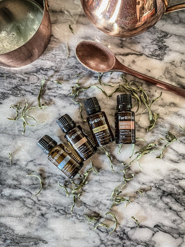 flatlay of far and wild essential oils on white marble counter with wooden spoon