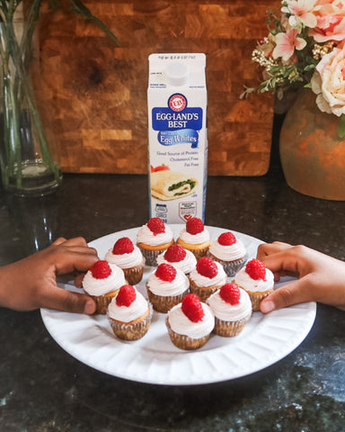 two kids hands reaching for raspberry mojito cupcakes with carton of egglands best 100% egg whites behind