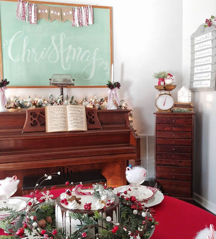 Piano with chalk board over it and Christmas table in front with faux cake