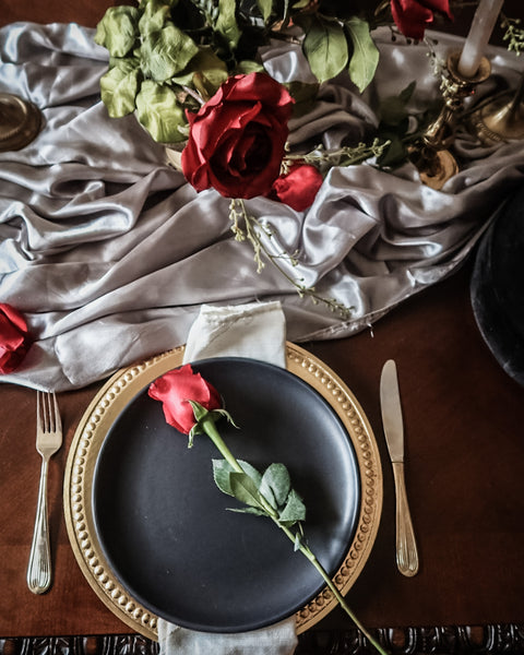 Flatlay of black gold and silver tablescape with red roses