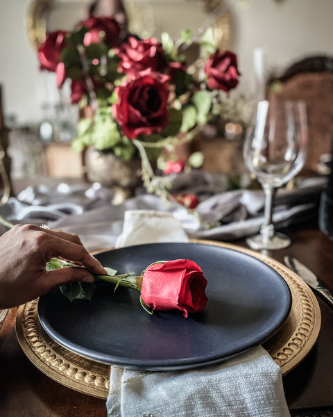 Placing red rose on black plate with gold charger
