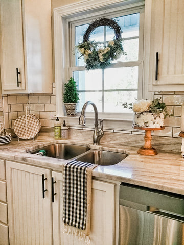 faux cake in kitchen beside sink with wreath in window