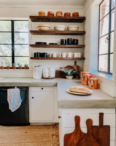faux bread on counter top of kitchen with floating wooden shelves in background