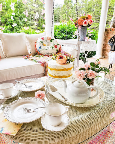 faux cake with pink flowers on patio table with white tea set