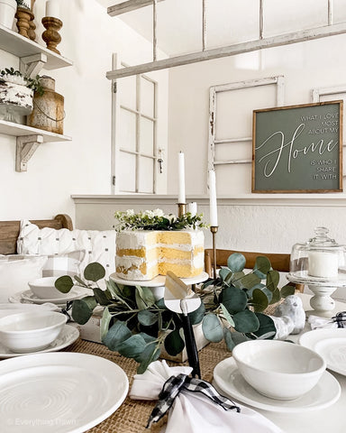 faux cake centerpiece on dining table with white dishes