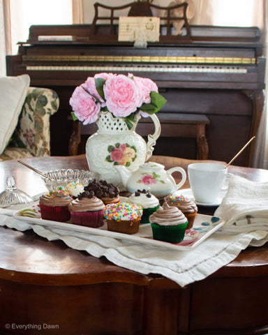 cupcakes on tray set on table with vase and flowers