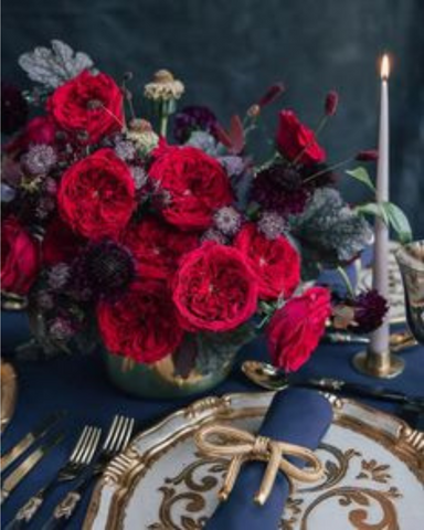 David Austin red roses with gold and blue place setting and thin taper candle